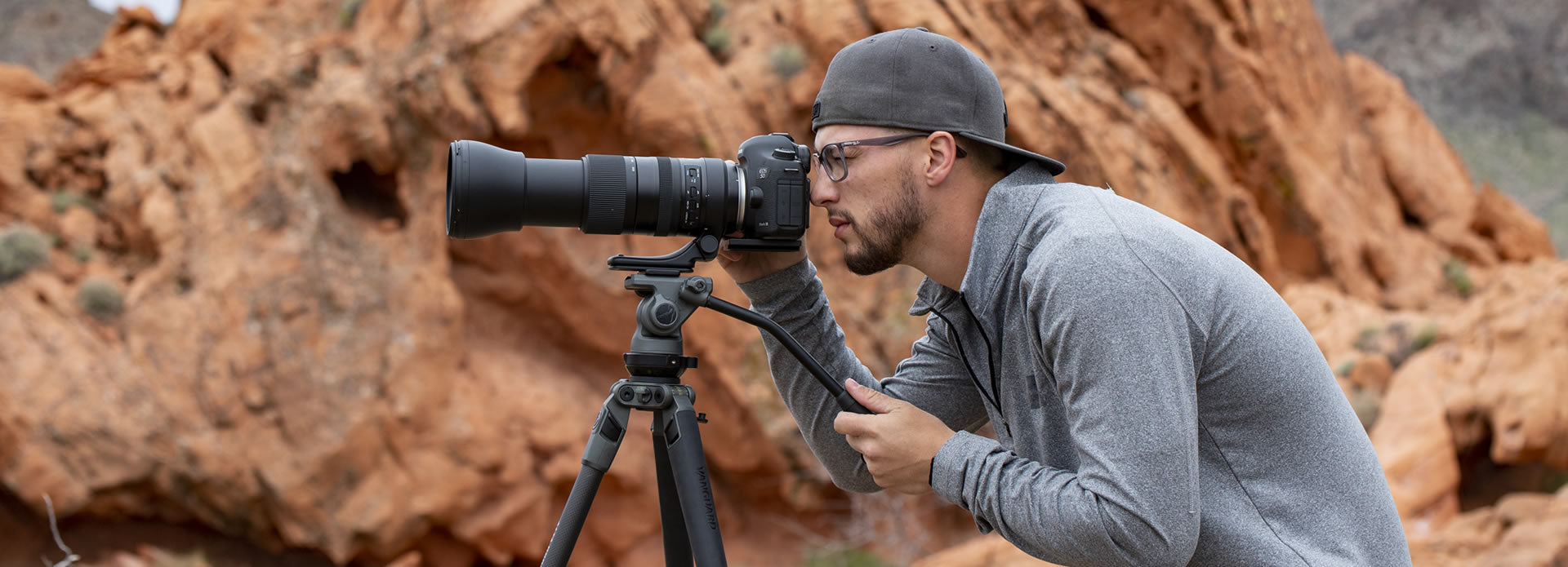 Fotógrafo deportivo haciendo una toma con su cámara y objetivo sobre un trípode de vídeo