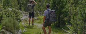 Observador con su mochila para telescopios y monopie subiendo una ladera