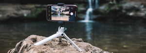 Mini-trípode para smartphone con un móvil encima haciendo una foto de una cascada