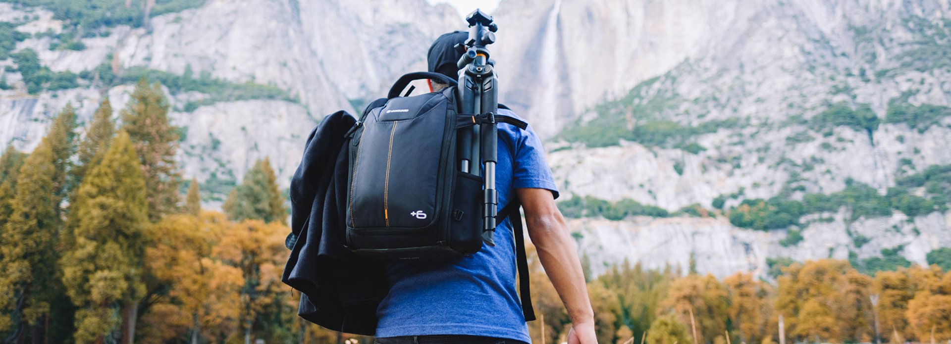 Fotógrafo con mochila de cámara a la espalda caminado por un montaña