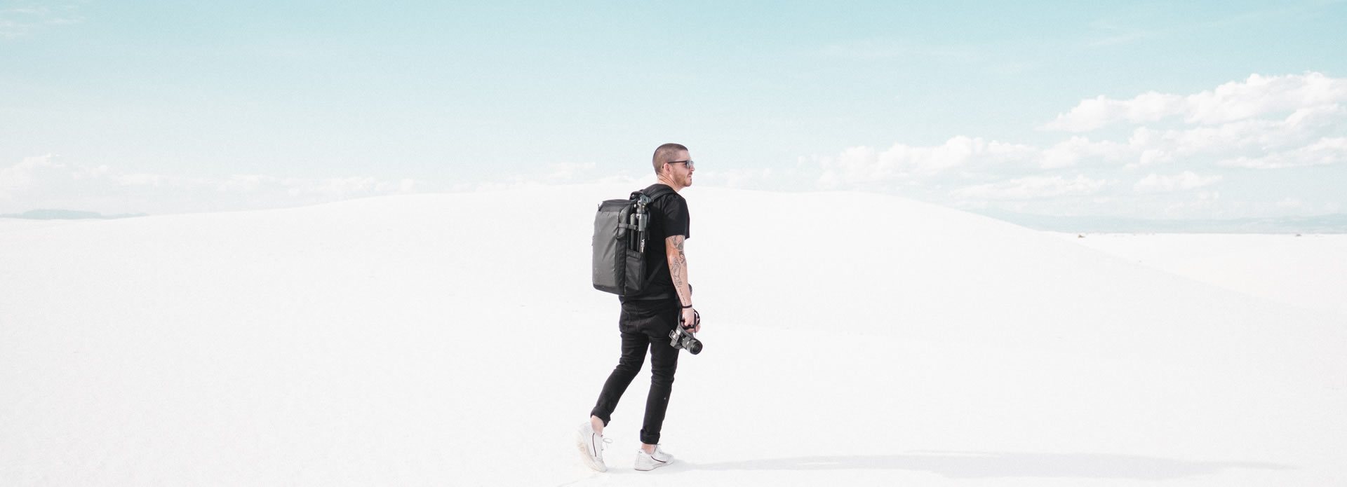 fotógrafo con una mochila de la serie Veo y su cámara caminando por un desierto